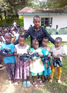 Pastor Kevin giving Sponsored children New shoes and School uniforms